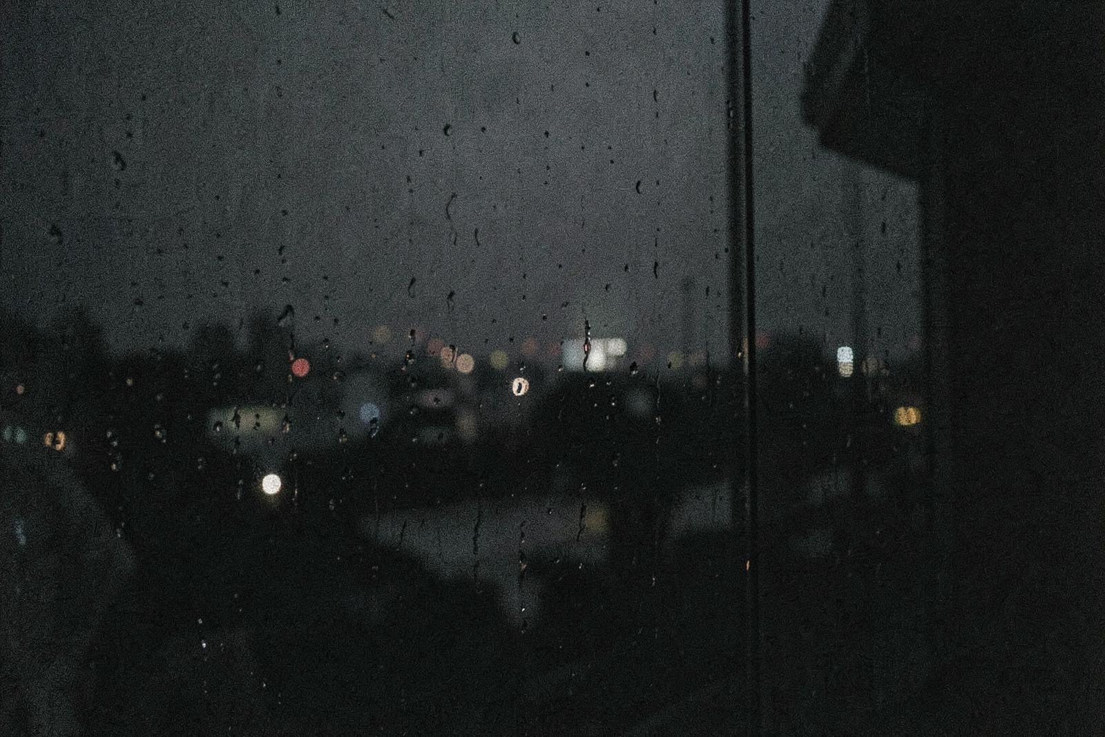 Rain on a dark window with distant blurred city lights