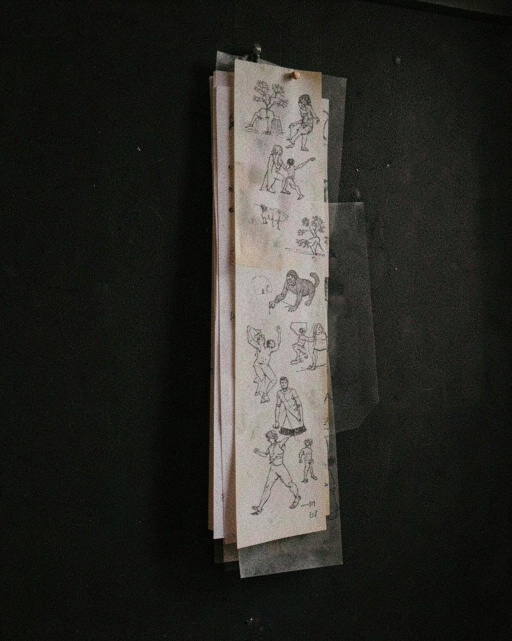 Translucent drawing sheets pinned in layers to a dark wall